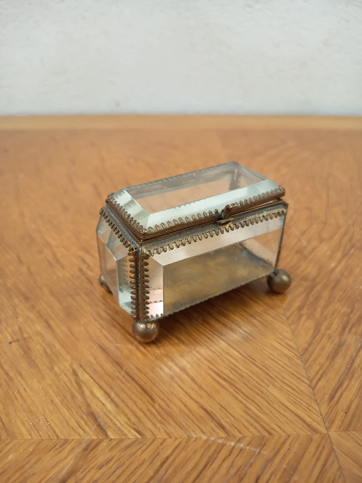 Boîte à bijoux ancienne en verre biseauté et laiton patiné, posée sur petits pieds boule, avec système de fermeture cassé.