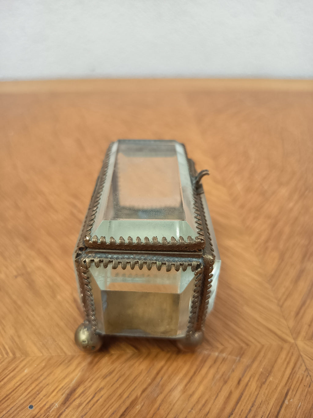 Boîte à bijoux ancienne en verre biseauté et laiton patiné, posée sur petits pieds boule, avec système de fermeture cassé.