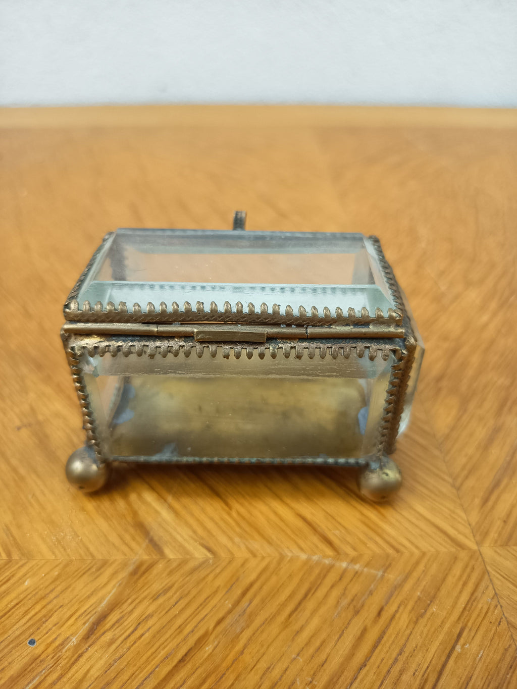 Boîte à bijoux ancienne en verre biseauté et laiton patiné, posée sur petits pieds boule, avec système de fermeture cassé.