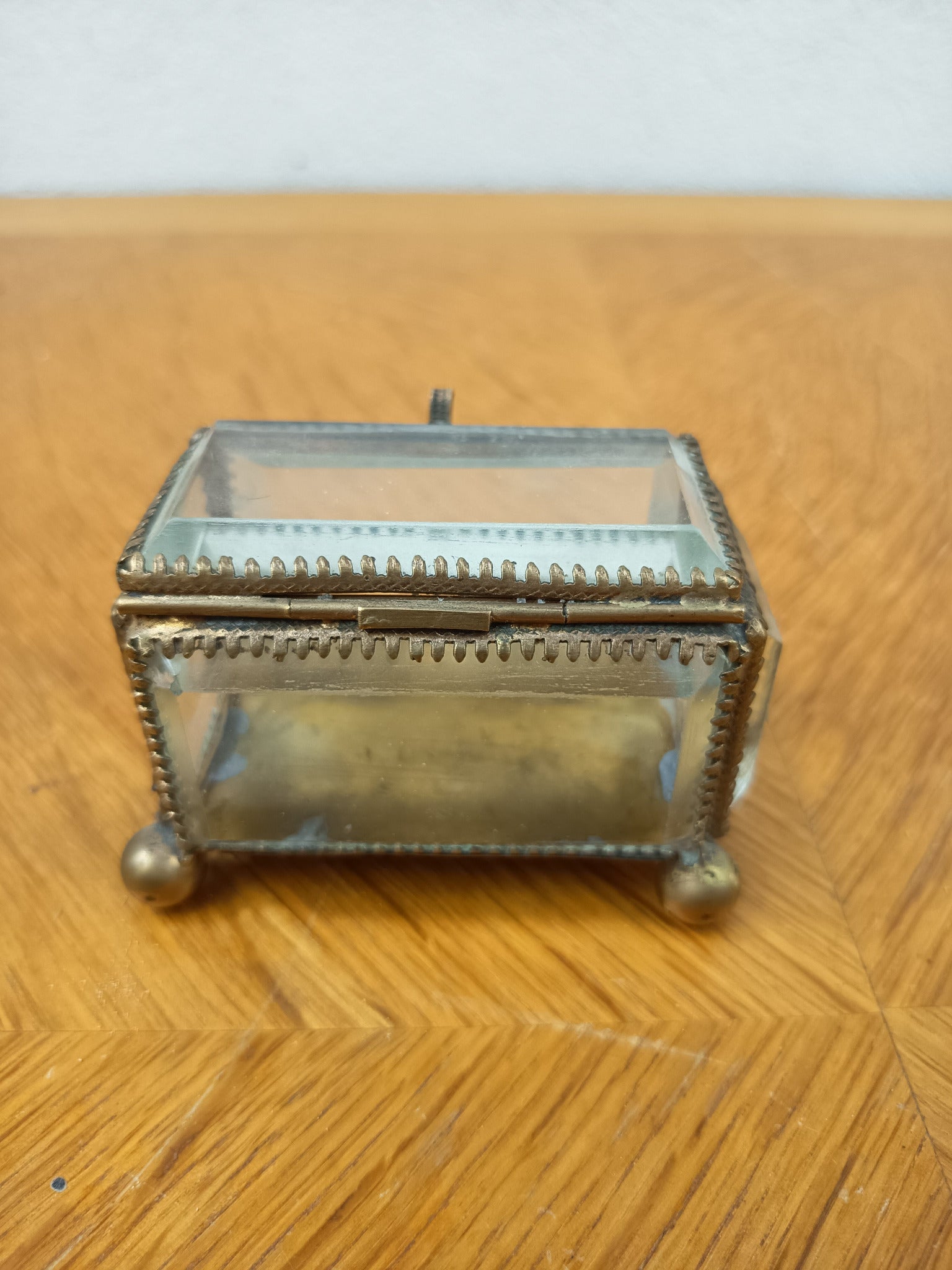 Boîte à bijoux ancienne en verre biseauté et laiton patiné, posée sur petits pieds boule, avec système de fermeture cassé.