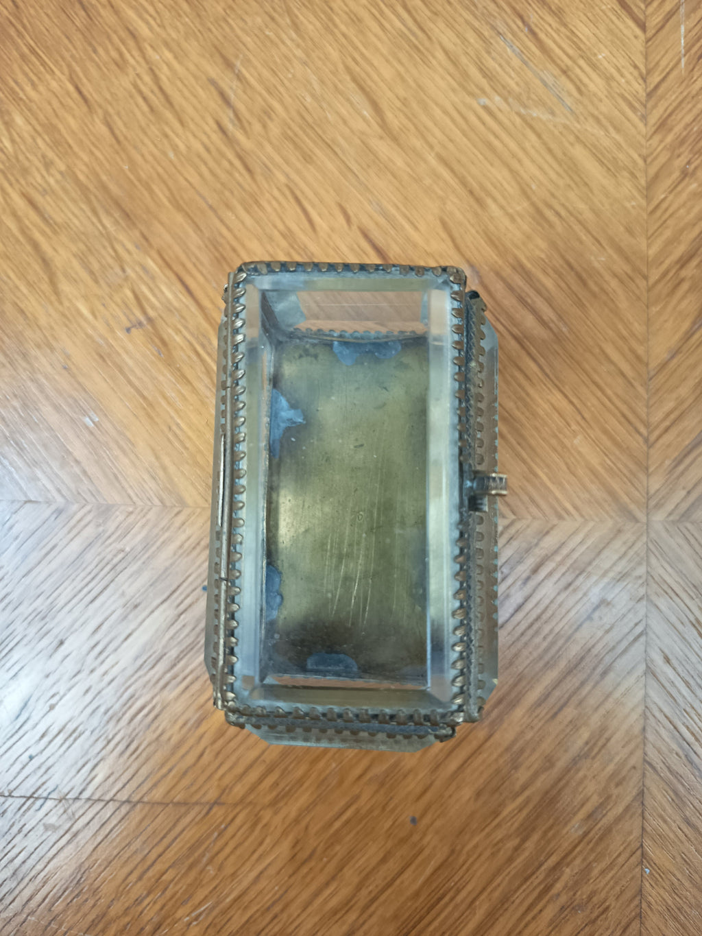 Boîte à bijoux ancienne en verre biseauté et laiton patiné, posée sur petits pieds boule, avec système de fermeture cassé.