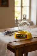 Ensemble publicitaire Ricard vintage composé d’un cendrier jaune en Opalex et d’une carafe Ricard en verre.