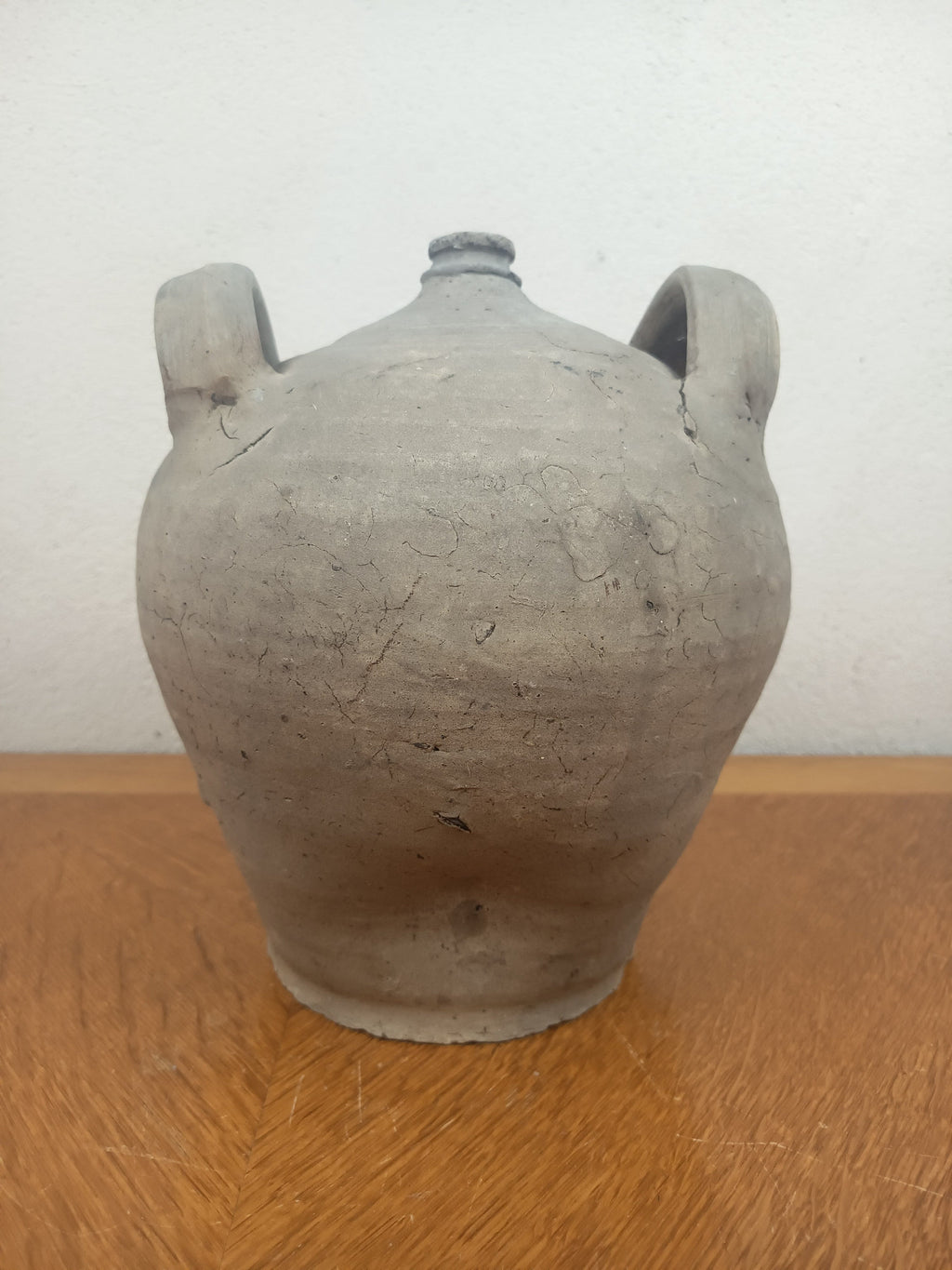 Jarre ancienne en terre cuite artisanale à patine grise, 26 cm de haut et 18 cm de diamètre au plus large.