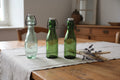 Lot de trois bouteilles anciennes Bolach et E Poirier en verre vert avec bouchons mécaniques