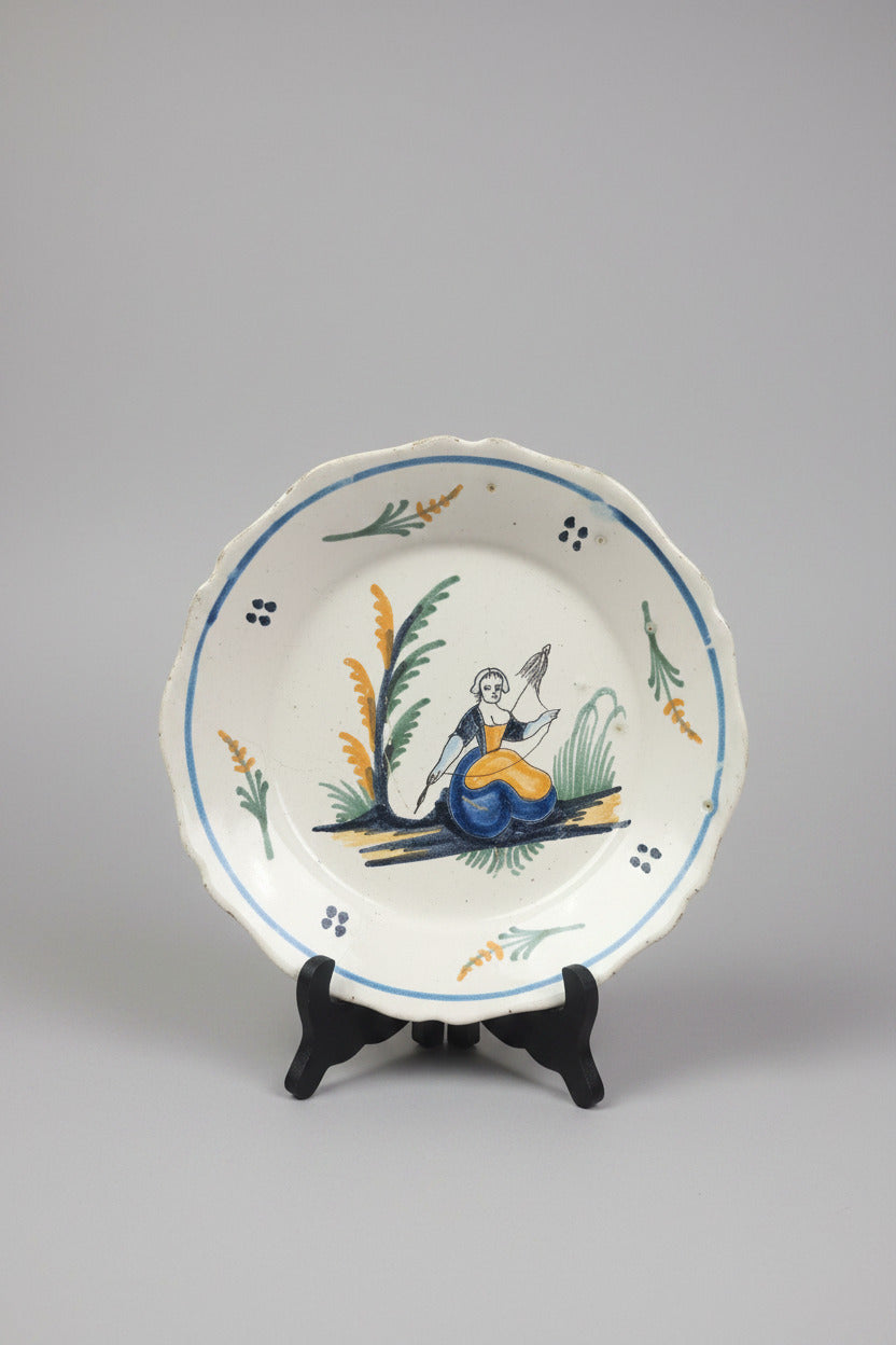 Assiette ancienne en faïence de Nevers du XVIIIe siècle, décor polychrome populaire représentant une fileuse à la quenouille. Diamètre 23 cm.