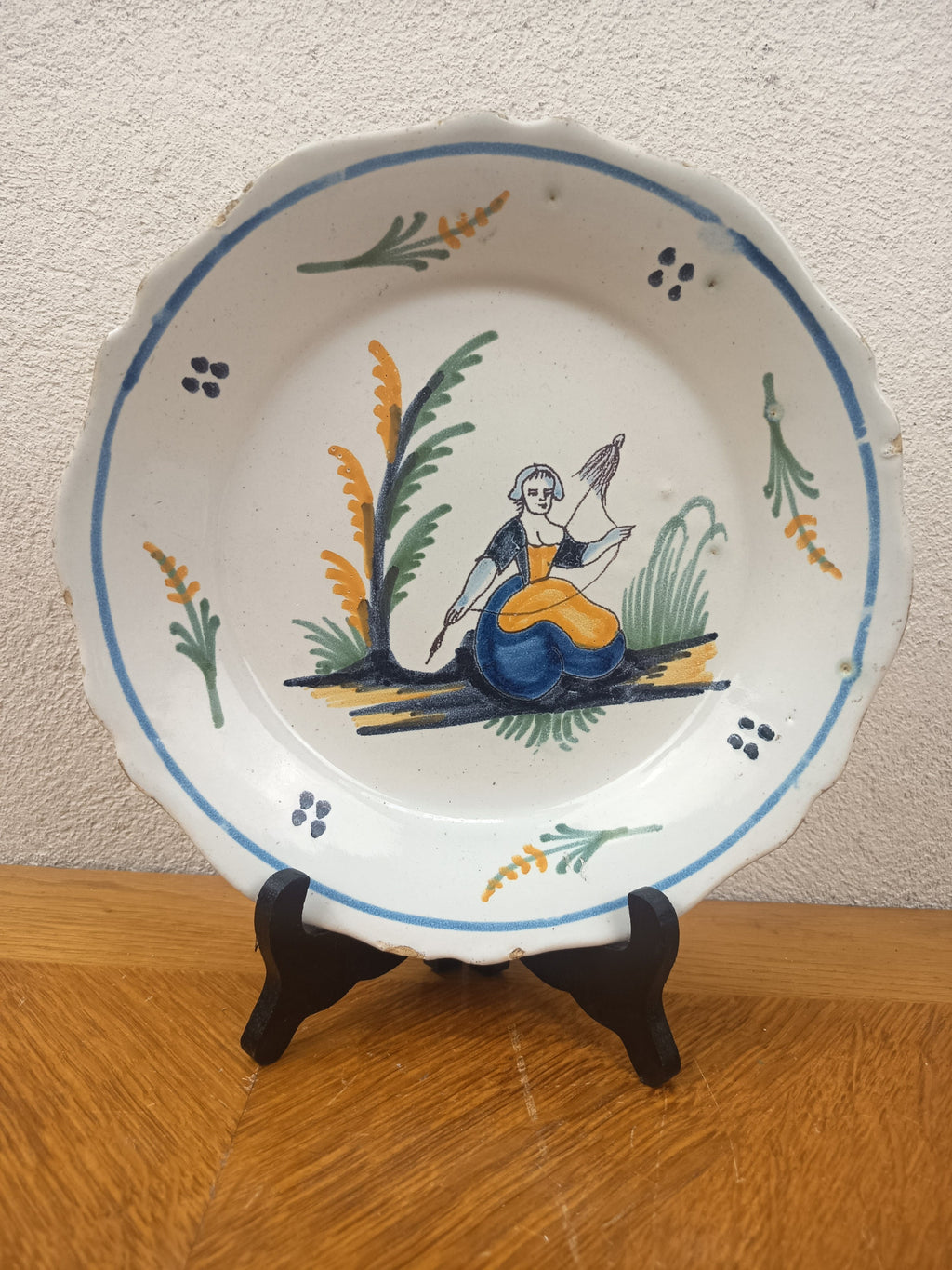 Assiette ancienne en faïence de Nevers du XVIIIe siècle, décor polychrome populaire représentant une fileuse à la quenouille. Diamètre 23 cm.