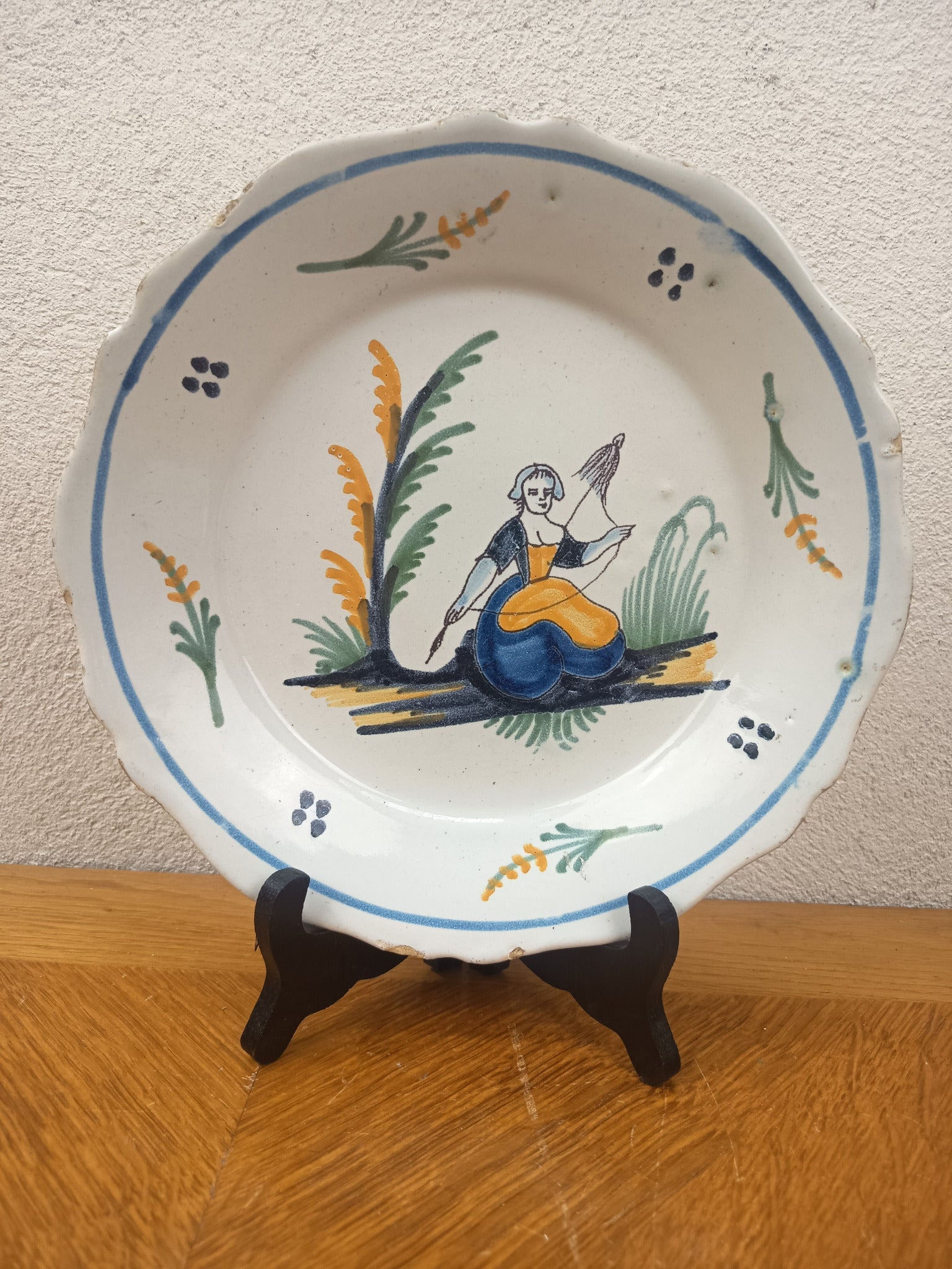 Assiette ancienne en faïence de Nevers du XVIIIe siècle, décor polychrome populaire représentant une fileuse à la quenouille. Diamètre 23 cm.
