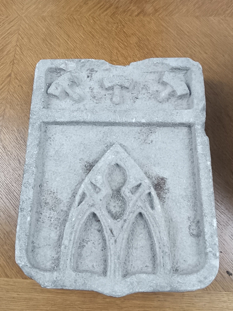 Écu en pierre claire sculpté en relief d’outils évoquant le métier de sculpteur ou de tailleur de pierre.