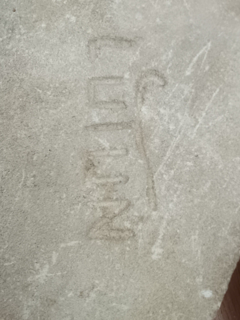 Écu en pierre claire sculpté en relief d’outils évoquant le métier de sculpteur ou de tailleur de pierre.