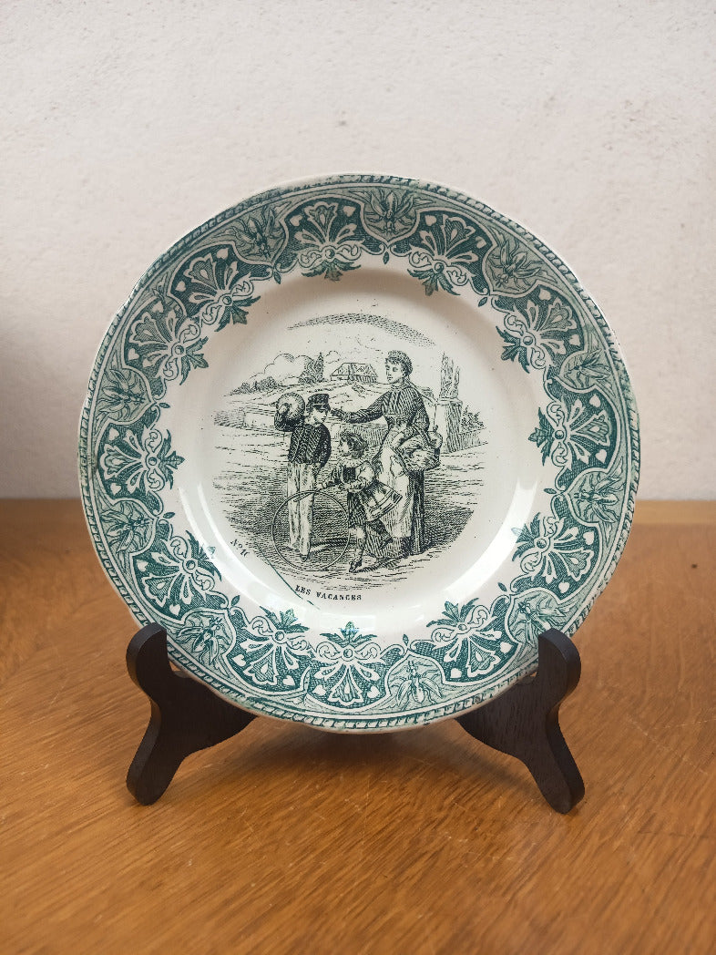 Assiette parlante Creil et Montereau « Les Vacances » no 16, décor vert représentant deux enfants et une femme, diamètre 19,5 cm.