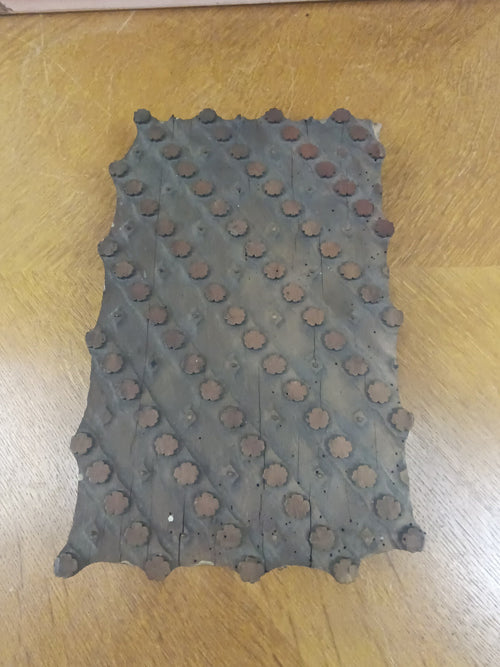 Ancienne planche d’impression textile de 37 × 23 cm, avec rosettes en relief et picots en cuivre sur un support en bois patiné.
