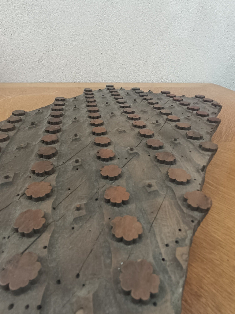 Ancienne planche d’impression textile de 37 × 23 cm, avec rosettes en relief et picots en cuivre sur un support en bois patiné.