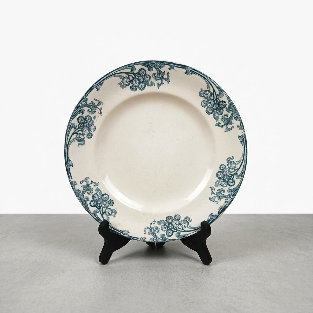 Assiette ancienne Longwy Les Églantines en terre de fer, décor floral bleu-vert sur fond ivoire, diamètre 23,5 cm.