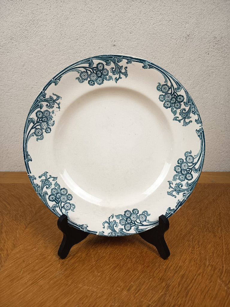 Assiette ancienne Longwy Les Églantines en terre de fer, décor floral bleu-vert sur fond ivoire, diamètre 23,5 cm.